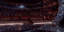 a robot is sitting on a stage in front of a crowd at an awards show .