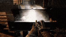 a person is holding a gun in a dark room with smoke coming out of it