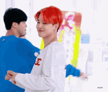 a man with red hair is wearing a white sweater and a blue shirt .