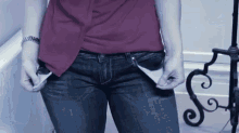 a woman wearing a red shirt and blue jeans has her pockets open