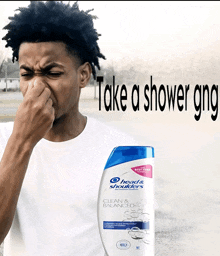 a man is covering his nose next to a bottle of head & shoulders shampoo