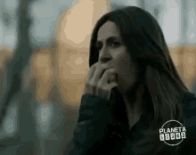 a woman is covering her mouth with her hand while looking at something .