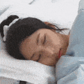 a young girl is sleeping on a bed with her eyes closed