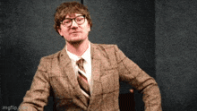 a man wearing glasses and a plaid suit is making a face