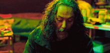 a man with long curly hair and a beard is sitting in a dark room with the words " the 20th century girl " above him