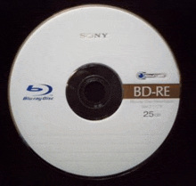 a sony branded blu ray disc is sitting on a black surface .