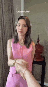 a woman in a pink vest and pants is shaking hands with another woman .