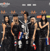 a group of people standing in front of a wall that says eurovision on it