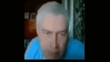 a close up of a man 's face with a blue shirt on .