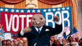 a man in a suit stands in front of a sign that says vote rob