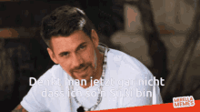 a man in a white shirt with a necklace around his neck says denkt man jetzt gar nicht