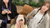 three women are standing next to each other and one of them is wearing a dog hat on her head .