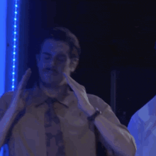 a man in a shirt and tie is dancing in a dark room .
