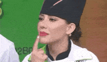 a woman in a chef 's hat is making a funny face with her finger on her lips .