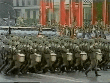 a parade of soldiers marching down a street with drums in their hands .