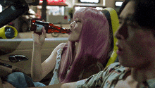a woman with pink hair is drinking a bottle of beer