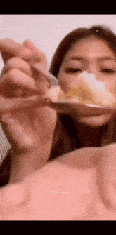 a woman is holding a spoon in front of her mouth .