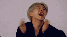 a close up of a person laughing with their mouth open and their hands in the air .