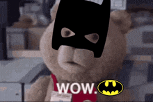 a teddy bear is wearing a batman mask and the word wow is above it