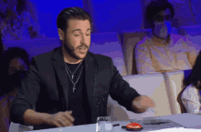 a man with a cross necklace sitting at a table