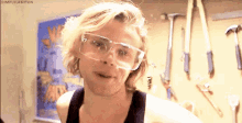 a man wearing safety glasses is making a funny face in a workshop .