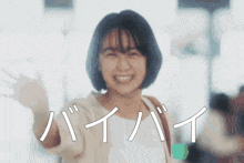 a woman is smiling and waving in front of a sign that says bye