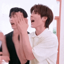 a couple of young men are laughing and clapping their hands together .