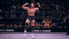 a wrestler stands in a ring with the words ring of honor behind him