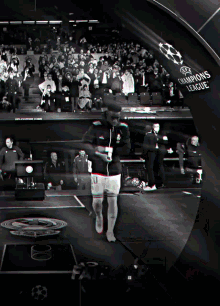 a black and white photo of a soccer player in front of a champions league banner