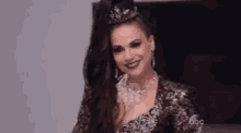 a woman with long black hair and a crown on her head is wearing a sequined dress and necklace .