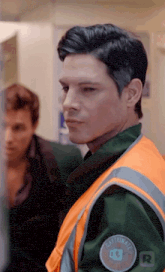 a man wearing an orange vest with the letter r on the back