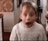a young boy is making a surprised face in a room .