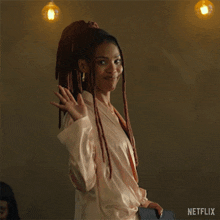 a woman with dreadlocks is standing in front of a man and waving at him .