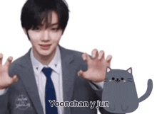 a man in a suit and tie is standing next to a cat with the words yoonchan y jun written on it .