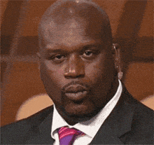 a bald man wearing a suit and tie is blowing a kiss