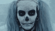 a close up of a woman with a skull makeup on her face .