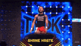 a wrestler named shane haste stands on a stage