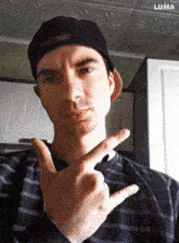 a man wearing a black hat and a striped shirt is making a peace sign with his hands