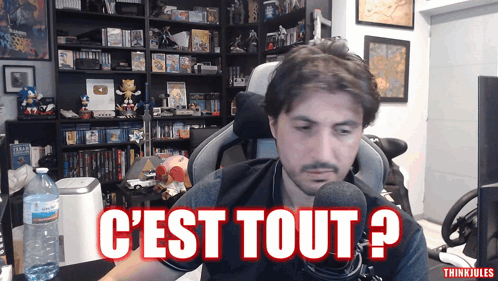 a man sitting in front of a microphone with the words c'est tout written in red