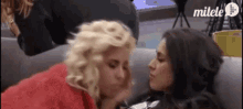 two women are kissing each other on the cheek on a couch .