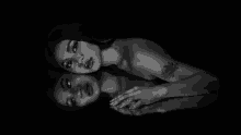 a black and white photo of a naked woman laying down with her reflection