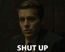 a man in a suit and tie says shut up in a dark room
