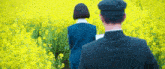 a man and a woman standing in a field of yellow flowers .
