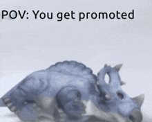 a toy dinosaur is laying on its back on a white surface with a caption that says `` pov : you get promoted '' .