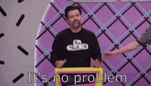 a man wearing a shirt that says no problem is standing in front of a sign that says it 's no problem