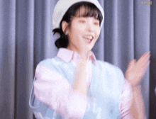 a woman wearing a pink shirt and a white hat is clapping