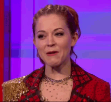 a woman in a red and gold dress is making a face .