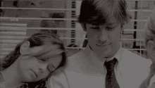 a man and a woman are sitting next to each other in front of a window in an office .