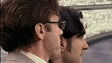 a man wearing glasses is looking at his reflection