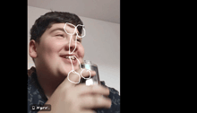 a boy holding a glass with a drawing of a penis on his face